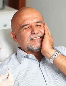 Man in dental chair holding jaw